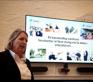 Daglig leder Anne Andersen hos iVekst står foran en tv skjerm som viser en presentasjon