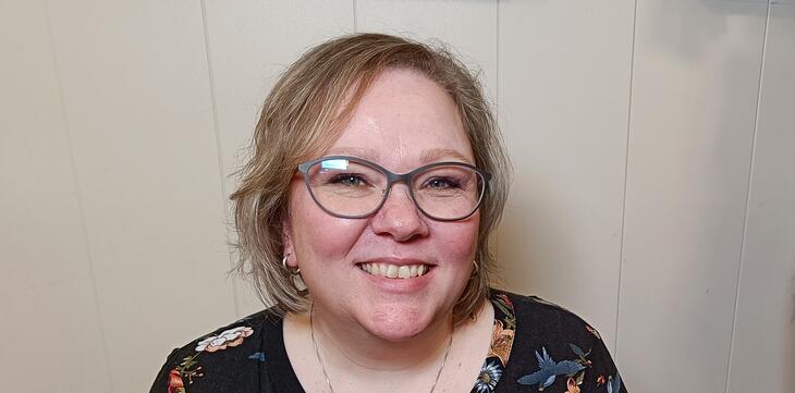 Bilde av en kvinne med briller som smiler til kamera